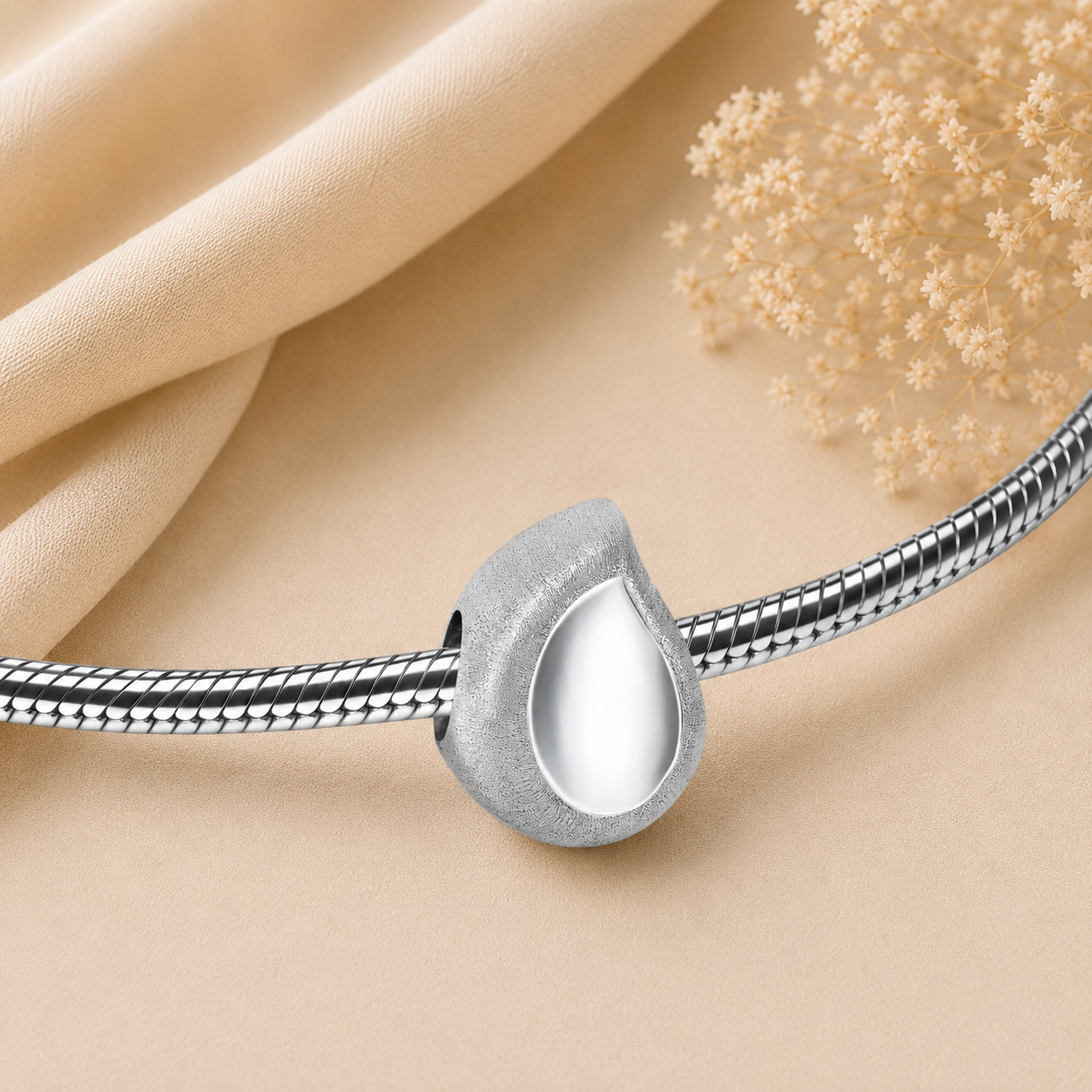 Druppelvormige asbedel van Sterling 925 zilver met matte en gepolijste afwerking, geschikt voor het bewaren van een symbolische hoeveelheid as aan een herinneringsarmband.